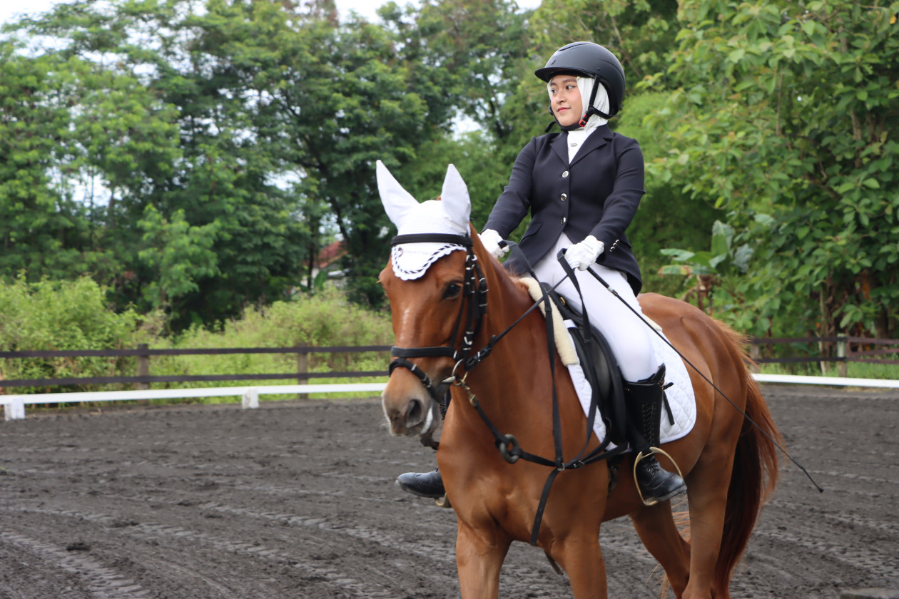 Participants in black jackets and white pants compete in the equestrian event at Porsenigama UGM, showcasing youth talent in three categories.