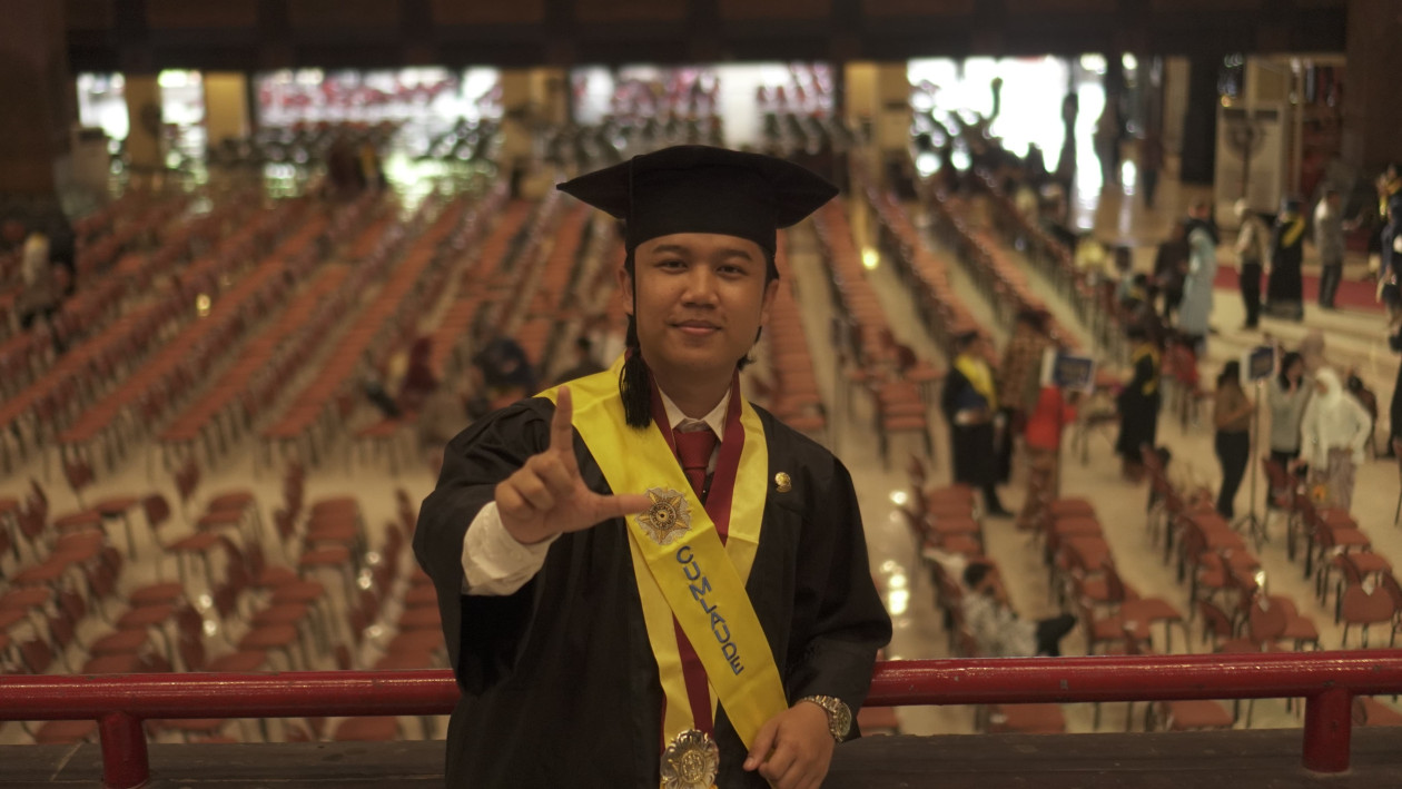 Wahyu Aji Ramadan, UGM Faculty of Law student, smiling in academic attire after graduating with distinction.