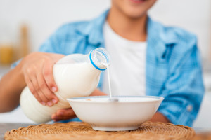 Illustration of a child pouring milk for his cereal