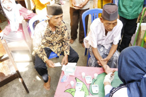 FK-KMK UGM volunteers distribute sacrificial meat packaged in teak leaves to residents in Yogyakarta.